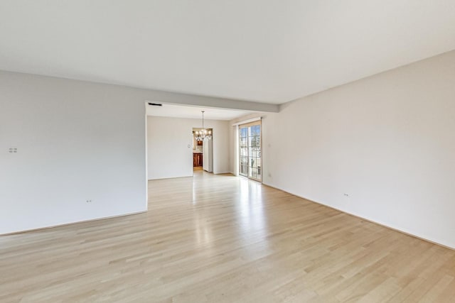 unfurnished room with a chandelier and light wood-style flooring