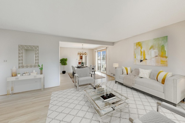 living room with light wood-style floors and a notable chandelier