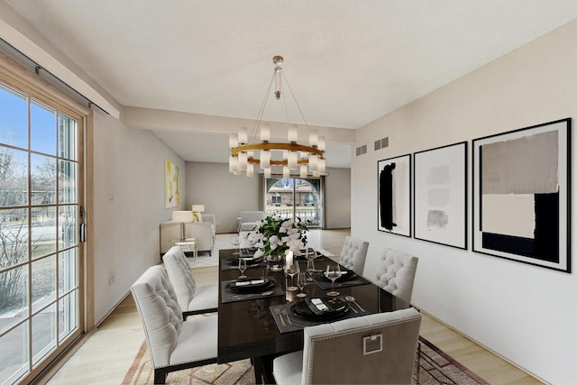 dining room featuring visible vents, light wood-style flooring, and an inviting chandelier