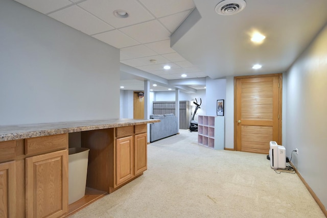 kitchen featuring a paneled ceiling and light carpet