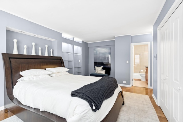 bedroom with ensuite bathroom and hardwood / wood-style floors