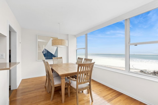 dining room featuring hardwood / wood-style floors, a water view, and a view of the beach