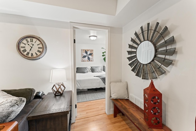 hall featuring visible vents, light wood-style flooring, and baseboards
