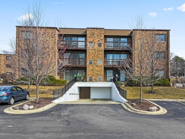 view of building exterior with driveway, an attached garage, and stairs