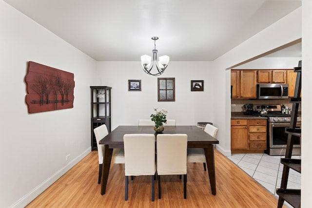dining area with baseboards, light wood finished floors, and a chandelier