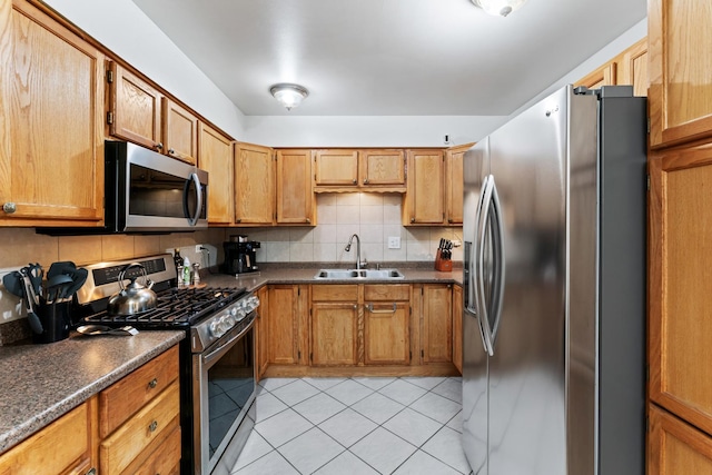 kitchen featuring a sink, stainless steel appliances, tasteful backsplash, and dark countertops