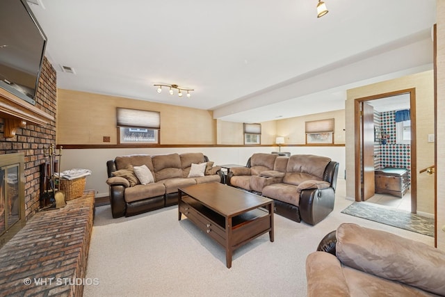 living area featuring a brick fireplace, visible vents, and carpet flooring