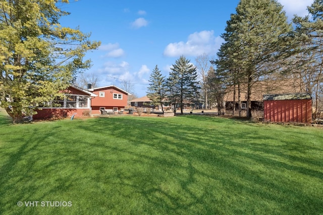 view of yard with a patio area, a shed, a sunroom, and an outbuilding