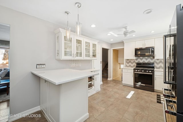 kitchen featuring light countertops, decorative backsplash, appliances with stainless steel finishes, glass insert cabinets, and white cabinets