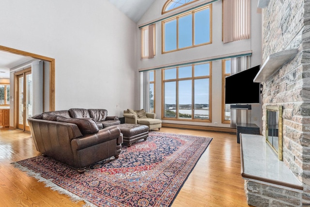 living room with a fireplace, plenty of natural light, light hardwood / wood-style floors, and high vaulted ceiling