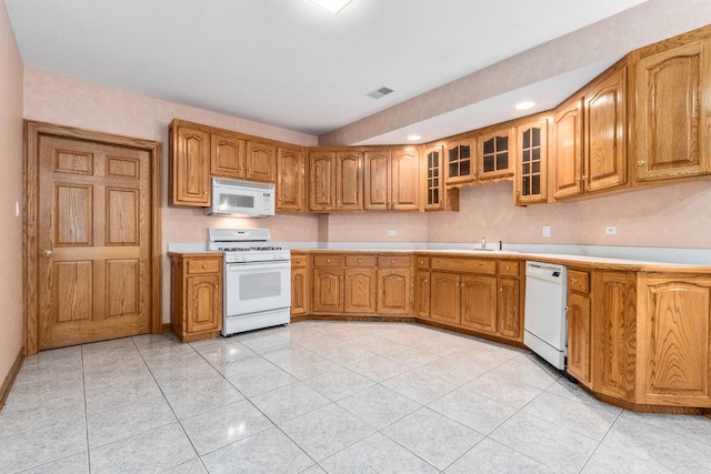 kitchen featuring white appliances, light tile patterned floors, and sink