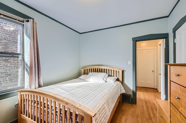 bedroom featuring crown molding, visible vents, and light wood-type flooring