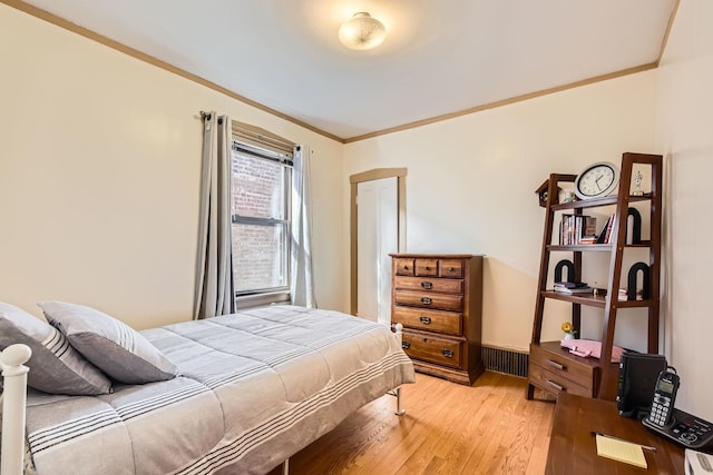 bedroom featuring ornamental molding and light wood finished floors