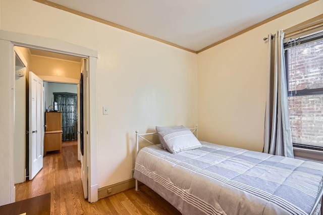 bedroom featuring light wood finished floors, baseboards, and ornamental molding