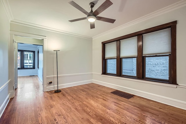 spare room with visible vents, wood finished floors, crown molding, and ceiling fan