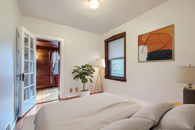 bedroom with wood finished floors, baseboards, and visible vents