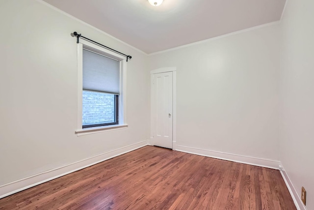 empty room featuring ornamental molding, baseboards, and wood finished floors
