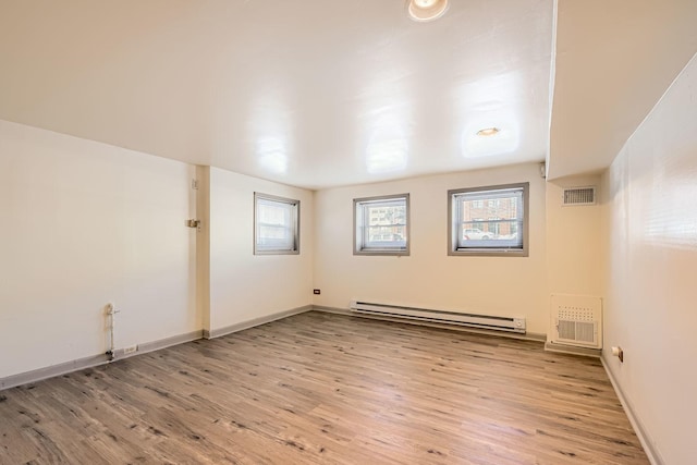 empty room with visible vents, a baseboard radiator, and light wood-type flooring