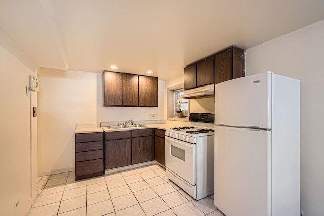 kitchen with white appliances, light countertops, dark brown cabinets, under cabinet range hood, and a sink