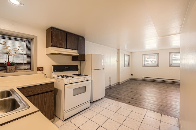 kitchen featuring white appliances, light countertops, dark brown cabinets, under cabinet range hood, and a baseboard radiator
