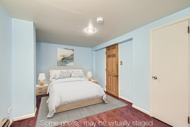 bedroom with baseboard heating, wood finished floors, and baseboards
