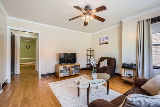 living room with light wood-style floors, ceiling fan, baseboards, and ornamental molding