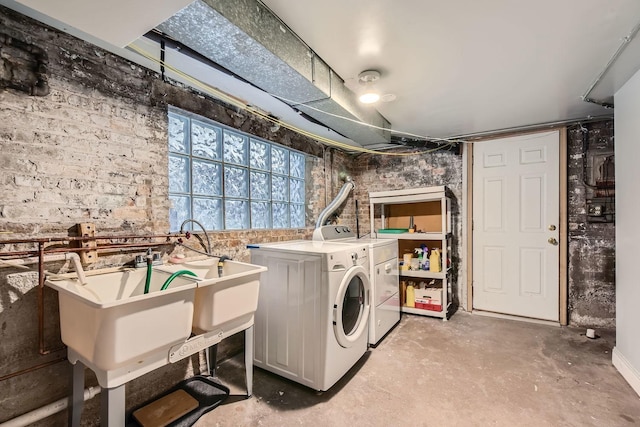 washroom with independent washer and dryer, brick wall, and laundry area