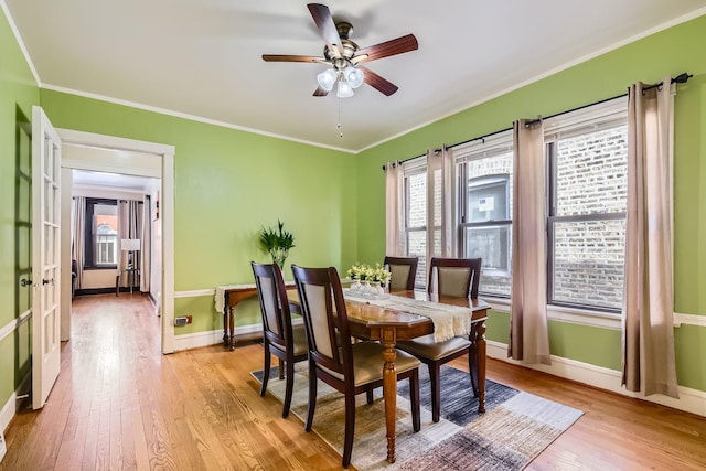 dining area featuring light wood finished floors, baseboards, ornamental molding, and ceiling fan