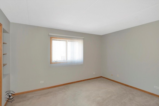 carpeted empty room featuring baseboards