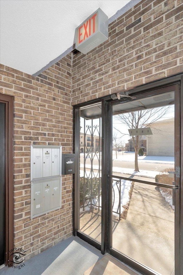 doorway to outside with brick wall and mail area