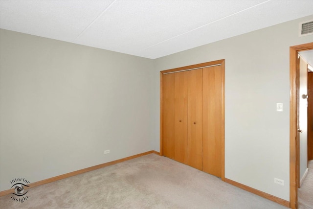 unfurnished bedroom with carpet floors, visible vents, baseboards, and a closet