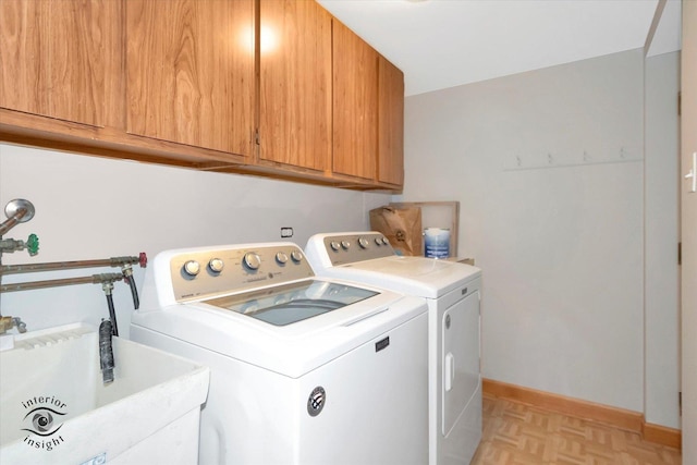 laundry room featuring cabinet space, washing machine and dryer, baseboards, and a sink