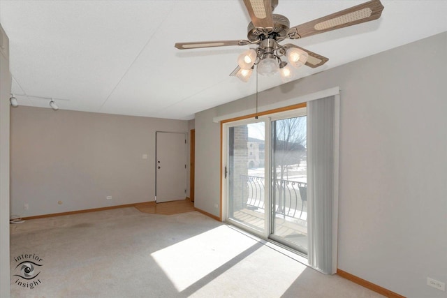 unfurnished room featuring light carpet, rail lighting, baseboards, and a ceiling fan