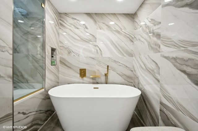 bathroom featuring tile walls and a tub