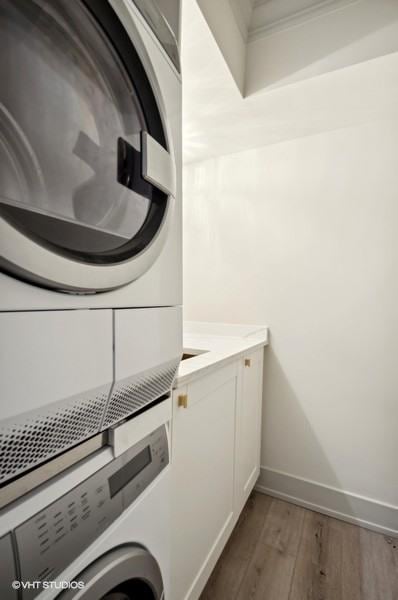 washroom featuring cabinets, dark hardwood / wood-style floors, and stacked washer and clothes dryer