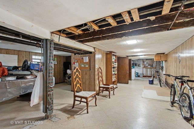 basement featuring light floors and wood walls