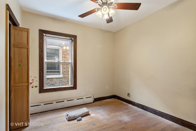 unfurnished room featuring a baseboard heating unit, light wood-style floors, a ceiling fan, and baseboards