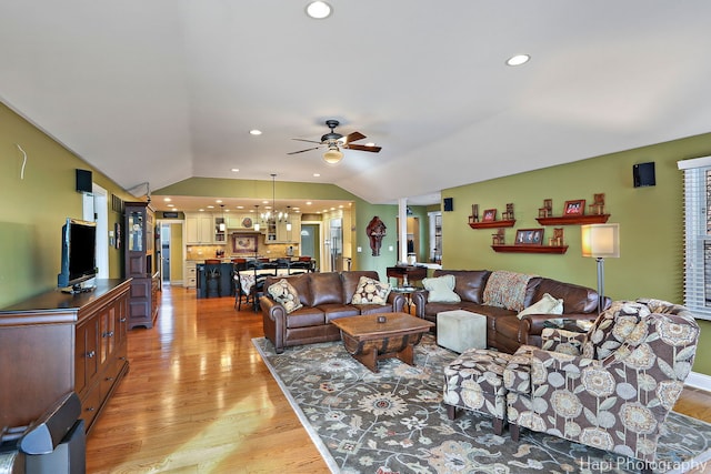 living area featuring light wood-style floors, lofted ceiling, ceiling fan with notable chandelier, and recessed lighting