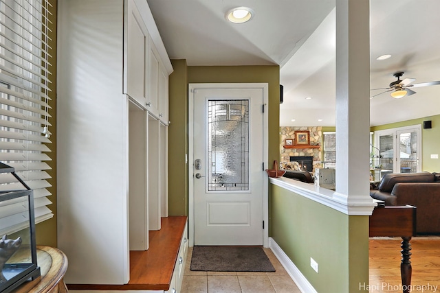 entryway featuring light tile patterned floors, baseboards, ceiling fan, a fireplace, and recessed lighting