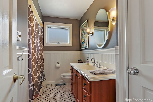 bathroom with toilet, a wainscoted wall, and vanity