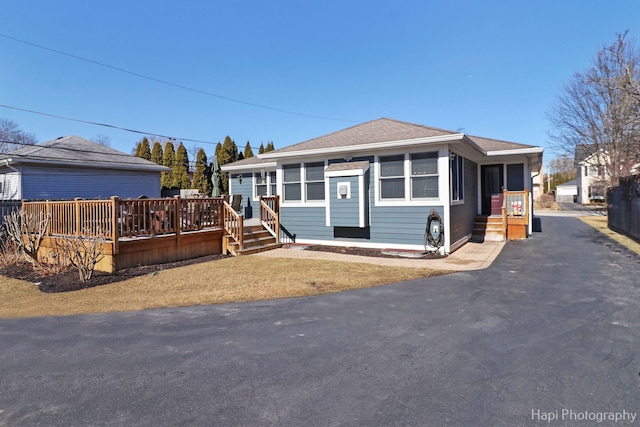 view of front of house with a shingled roof and a deck