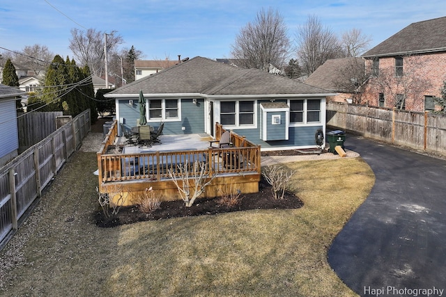 back of house featuring a deck, driveway, a shingled roof, and a fenced backyard