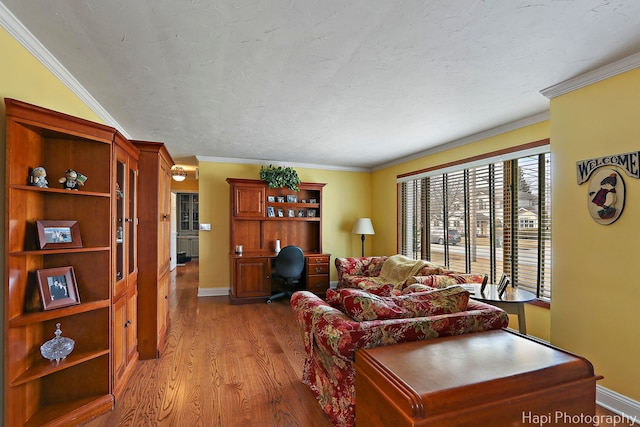 living area featuring baseboards, a textured ceiling, ornamental molding, and wood finished floors