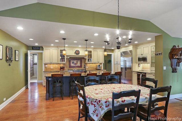 dining space with vaulted ceiling, wine cooler, light wood-style flooring, and baseboards