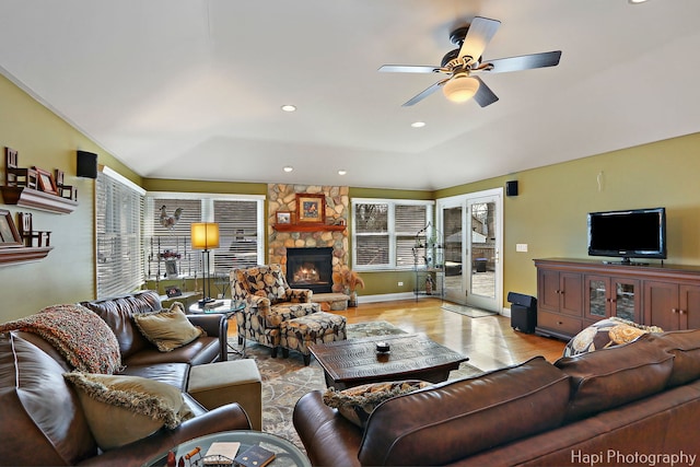 living room with light wood finished floors, recessed lighting, ceiling fan, a stone fireplace, and baseboards