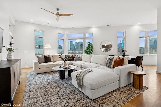 living room with light wood-style floors, recessed lighting, plenty of natural light, and baseboards