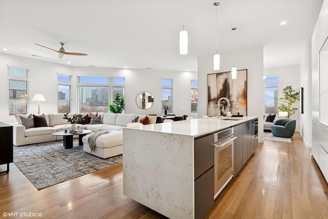 kitchen with light wood-type flooring, modern cabinets, open floor plan, and a sink