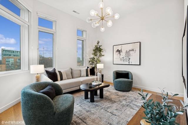 living room featuring a chandelier, wood finished floors, visible vents, and baseboards