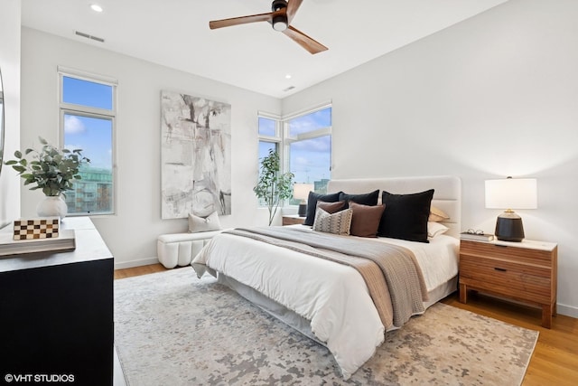 bedroom with light wood-style floors, visible vents, baseboards, and multiple windows