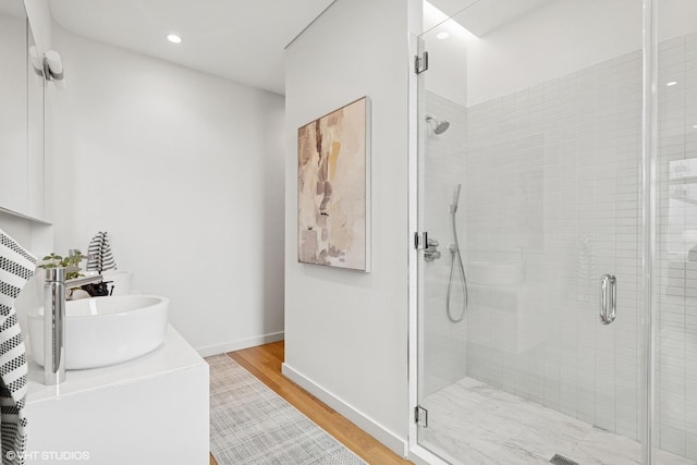 bathroom with a shower stall, baseboards, and wood finished floors